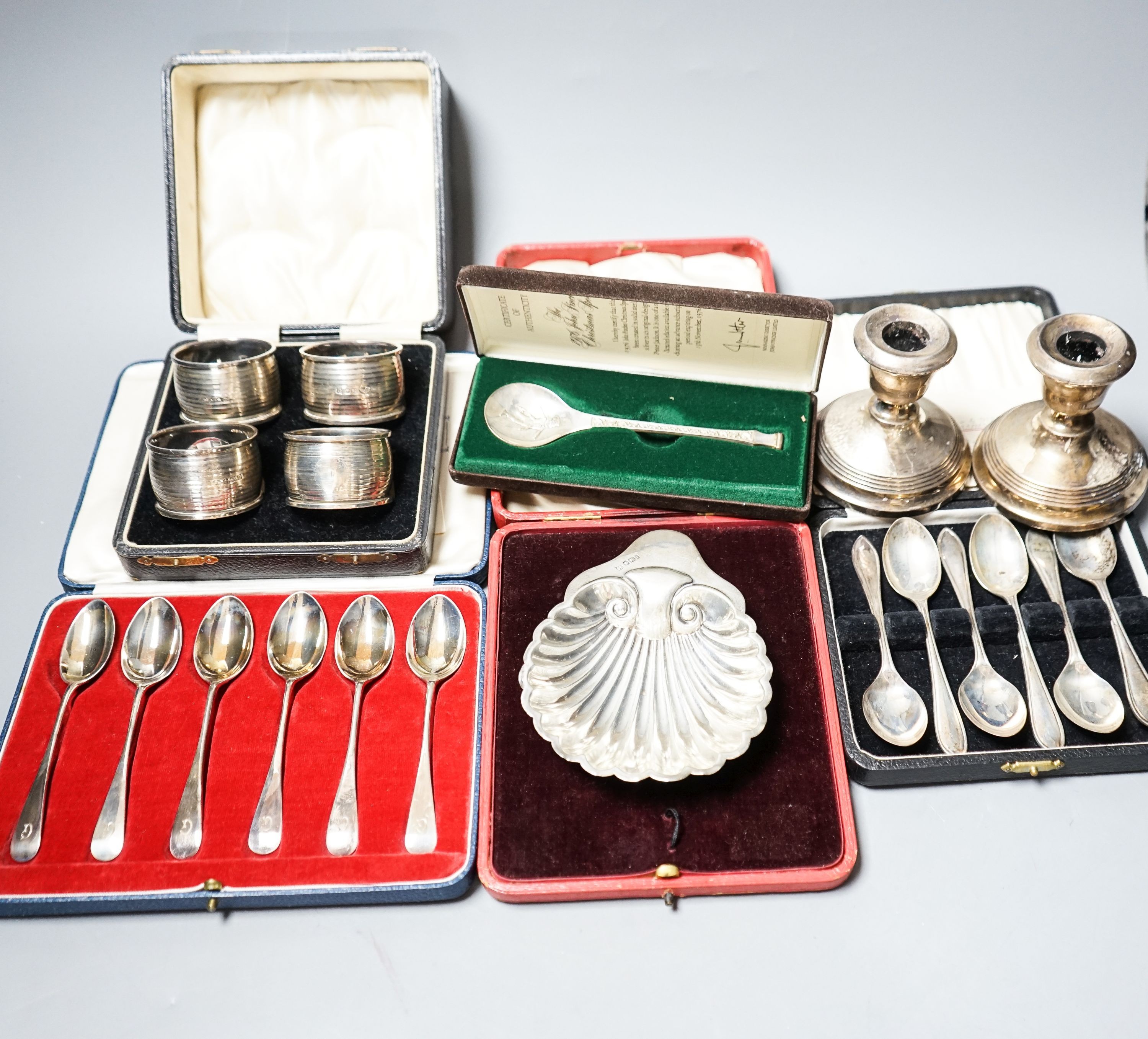 A cased pair of four 1920's silver napkin rings, four other cased items including butter shell and a pair of silver mounted dwarf candlesticks.